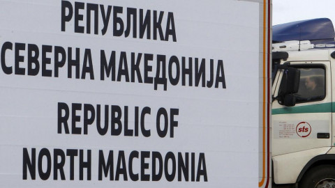 A truck driver waits behind a road sign at North Macedonia's southern border with Greece, near Gevgelija, in 2019