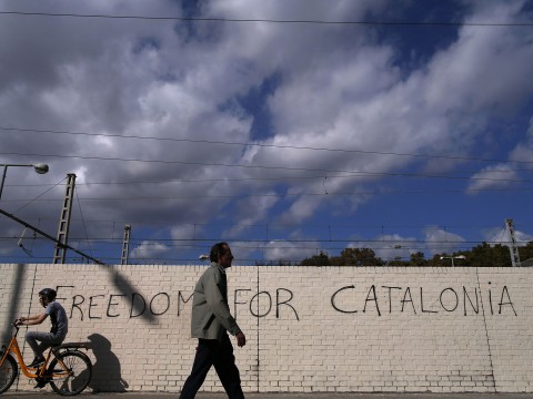 People pass in front of graffiti reading 