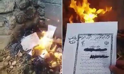 A government document is torched by an Iranian as anti-government unrest continues in the country