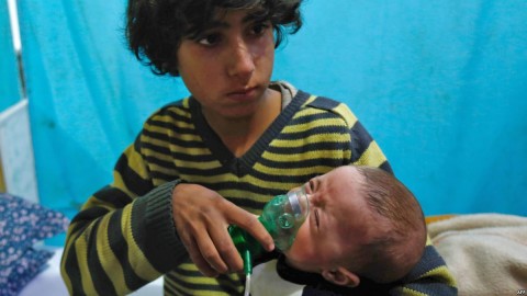 A Syrian boy holds an oxygen mask over the face of an infant at a makeshift hospital following a reported gas attack on the rebel-held besieged town of Douma, Jan. 22, 2018. Photo: AFP