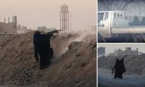 Female fighter: A woman dressed head to toe in black, including a burqa covering her face, fires an assault rifle as she fights for ISIS on the frontline