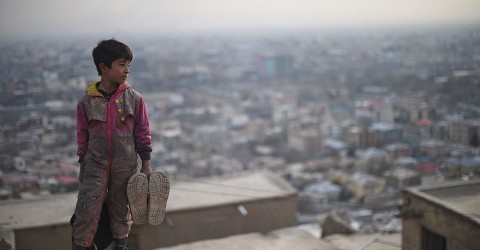 An Afghan shoe-shine boy Sameiullah, 11, looks on from a hillside towards the Karta-e-Sakhi cemetery, where he waits for customers daily in Kabul on February 10, 2015. Photo: Shah Marai / AFP / Getty