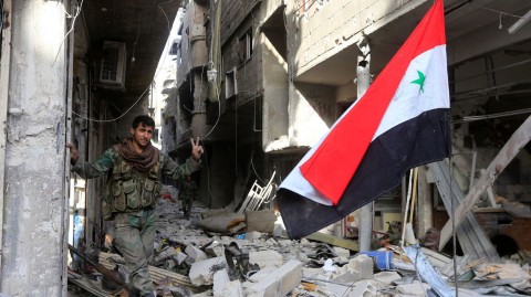 A member of the Syrian government forces stands at the entrance of Yarmouk refugee camp on Monday, the day that the military announced it had full control of Damascus and its outskirts. Photo: Louai Beshara/AFP/Getty Images